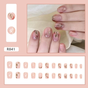 Unghie finte corte quadrate con bacche rosse e foglie d'oro su base rosa delicato