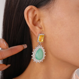 Detailed view of vintage teardrop earrings with yellow and green gemstones on a model