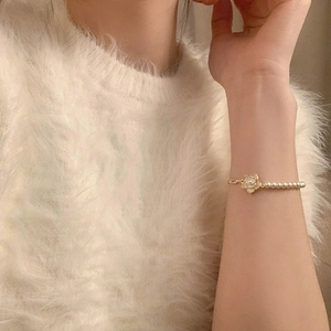 Detailed view of camellia pearl bracelet on a model wearing a soft white sweater