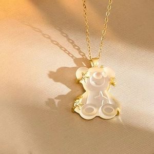 Detailed macro view of a gold-tone bear pendant with white resin and star accents