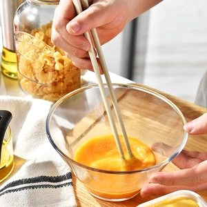 One-piece silicone spoon and chopsticks set whisking eggs in a glass bowl for cooking