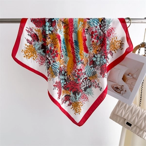 Detail of silk square scarf featuring vibrant floral patterns and red border accent