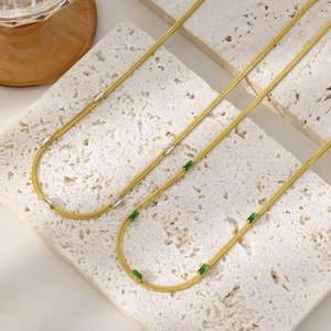 Detail of gold snake chains with green and white square cut zircon pendants