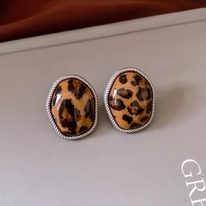 Détail de boucles d'oreilles ovales imprimé léopard avec cadre en métal argenté tressé