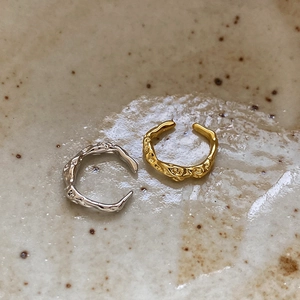 Close-up of gold and silver S925 sterling silver ear cuffs with irregular lava texture
