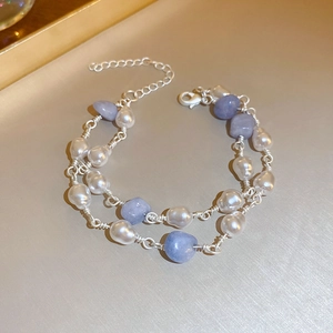Detailed close-up of double-layer bracelet with white pearls and purple stones