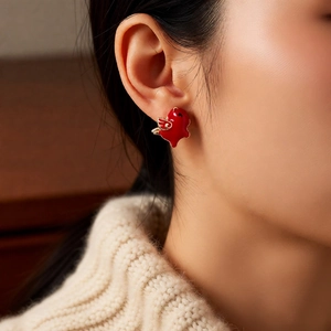 Close-up of model wearing red enamel horse pendant earrings with 18k gold plating
