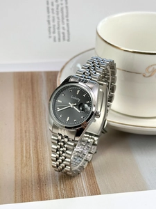 Detail view of silver metal strap women's watch with black dial and calendar feature