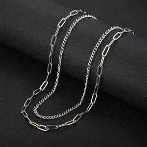 Macro detail of silver titanium steel double-layer necklace with OT buckle and Cuban links