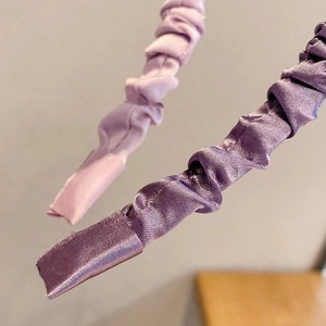 Detail of purple pleated satin headbands showing glossy fabric texture and edge finishing