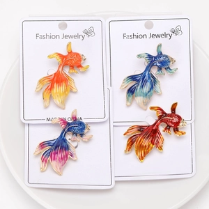 Detailed macro view of four colorful enamel goldfish brooches on fashion jewelry display cards