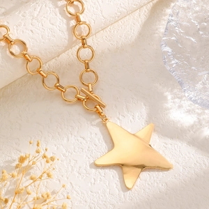 Close-up of golden chunky chain necklace with large star pendant and toggle clasp