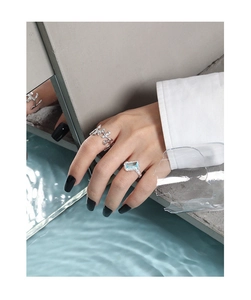 Detail of silver liquid metal hollow ring and blue gemstone set on model hand