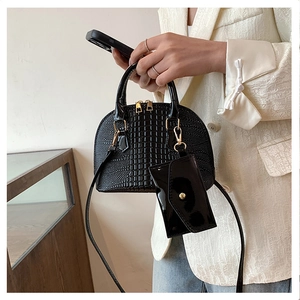 Close-up of black crocodile pattern shell bag with golden hardware and small pouch