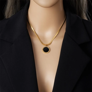 Vintage black Roman disc pendant necklace with gold chain on model in black suit