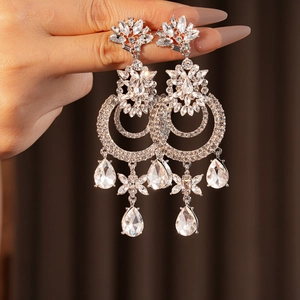 Détails de boucles d'oreilles vintage argentées avec strass superposés et pendentifs poires