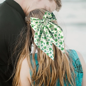 Close-up of a woman wearing a green four-leaf clover print bow hair clip in a natural setting