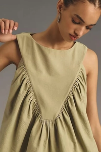 Detail of sage green sleeveless top showing V-shaped pleated stitching and fabric texture