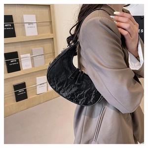 Detail of black crescent shoulder bag featuring textured cracked leather and silver hardware