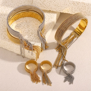 Detail of beaded tassel bracelets and rings in gold and silver on white stone