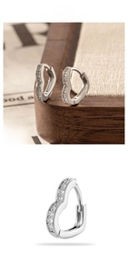 Detail of silver heart-shaped earrings with white cubic zirconia on a wooden display