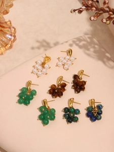 Detailed macro shot of tassel earrings featuring tiger eye stones and faux pearls
