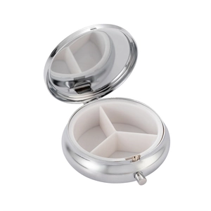Detail view of silver metal pill box with 3 compartments and a built-in mirror inside