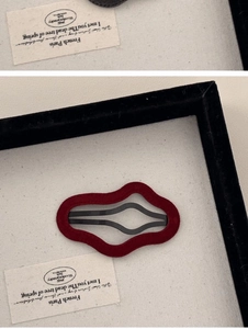 Detail of red flocked irregular geometric hair clip with black metal hollow center design
