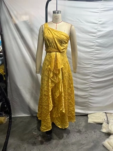 Detail of yellow one-shoulder lace dress with asymmetric ruffled hem and high waist line