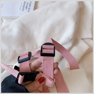 Detail showing pink adjustable shoulder strap with black buckle on canvas backpack