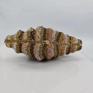 Detail of luxury conch-shaped evening clutch bag featuring striped multi-color rhinestones