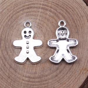 Silver gingerbread man metal charms for DIY jewelry on a natural wood base