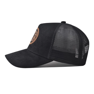 Detailed side view of black trucker hat with mesh back and circular leather badge