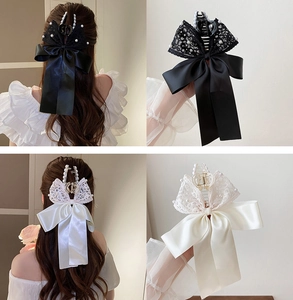 Close-up of elegant lace hair claws with pearls and ribbon bow details for women