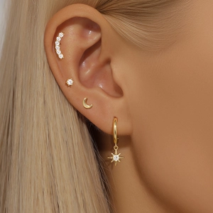 Close-up of gold S925 silver star and moon earring set worn on model ear