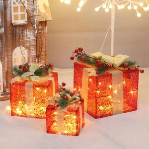 Detail of red lighted Christmas gift boxes with gold bows and warm LED lights