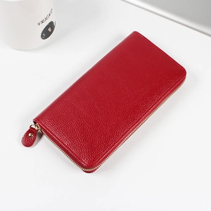 Red litchi texture leather long wallet with gold zipper on a minimalist white desk