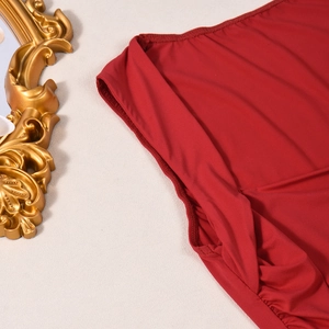 Close-up of seamless stitching on high-elastic deep red fabric top with golden frame