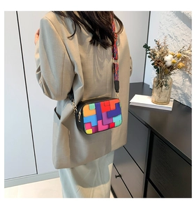 Close-up of a stylish crossbody bag with colorful geometric patterns on a model suit