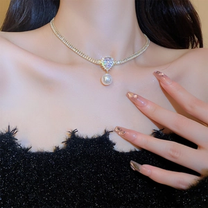 Close-up of a gold-plated pearl necklace with a teardrop zircon pendant on a model