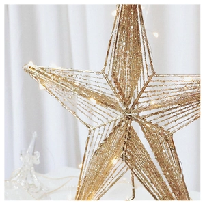 Close-up of golden wired Christmas star tree topper with sparkling glitter and warm LED lights