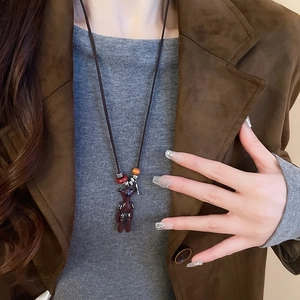 Detailed close-up of dark red bear pendant necklace with woven cord and vintage beads