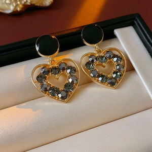 Gros plan de boucles d'oreilles dorées avec cercles noirs et cristaux en forme de cœur