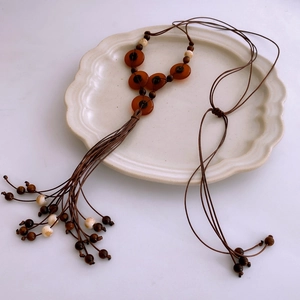 Detailed close-up of ethnic beaded necklace featuring red resin pendants and tassels