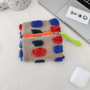 Detail of colorful plush storage bag with pom-poms, orange zipper and green lanyard