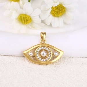 Macro shot of gold eye pendant with embedded diamonds and centered pearls on white background