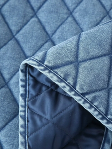 Detailed macro shot of the diamond quilted texture and ruffles on this blue bomber jacket