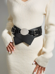 Detail of a wide black faux leather belt featuring a large silver circular metal buckle