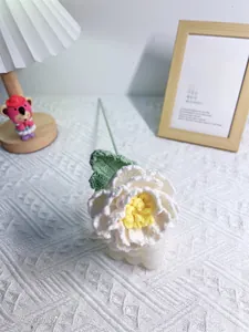 Detail of handmade crochet peony flower with white petals and yellow stamen on stand
