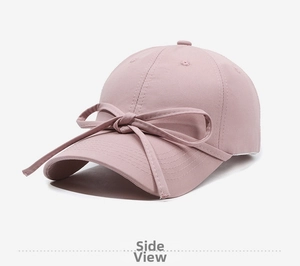 Detail view of pink cotton baseball cap featuring a long ribbon bow and side profile